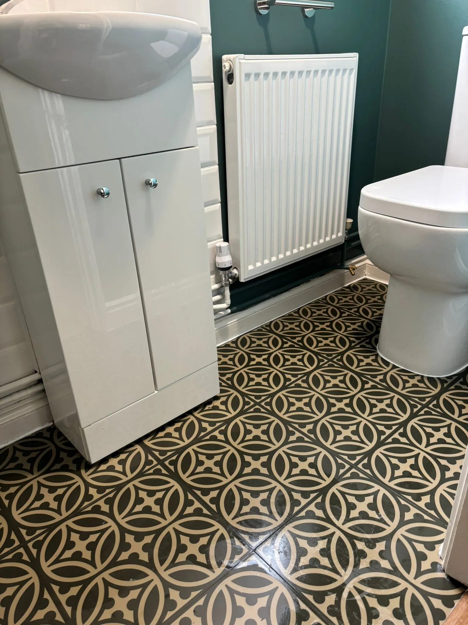 A bathroom with a toilet, sink, and radiator.