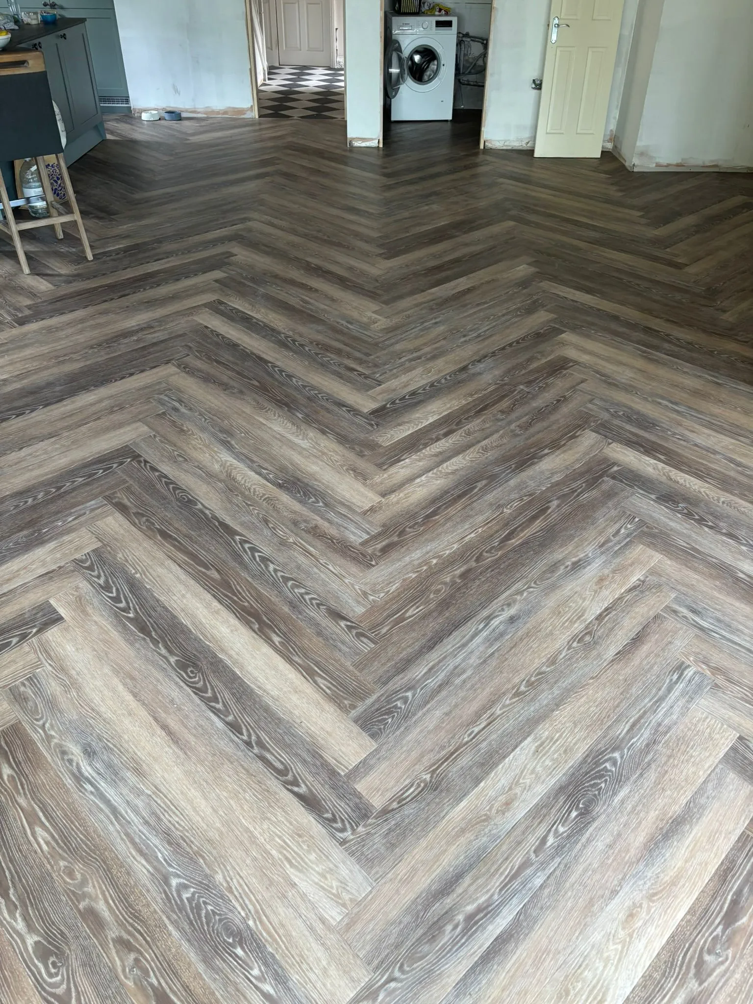 A wood floor in a house with a kitchen in the background.