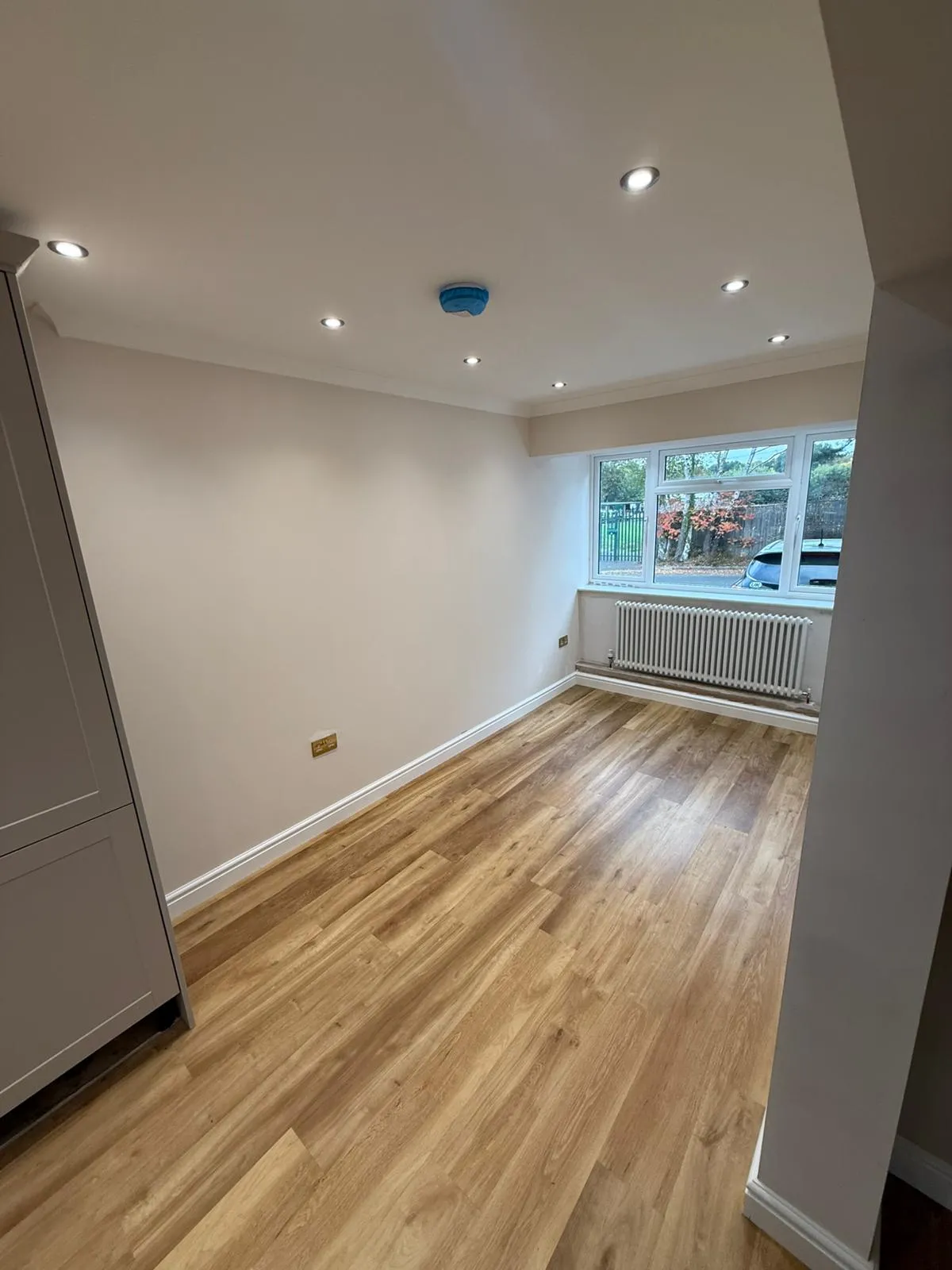 An empty room with hard wood floors and a radiator.