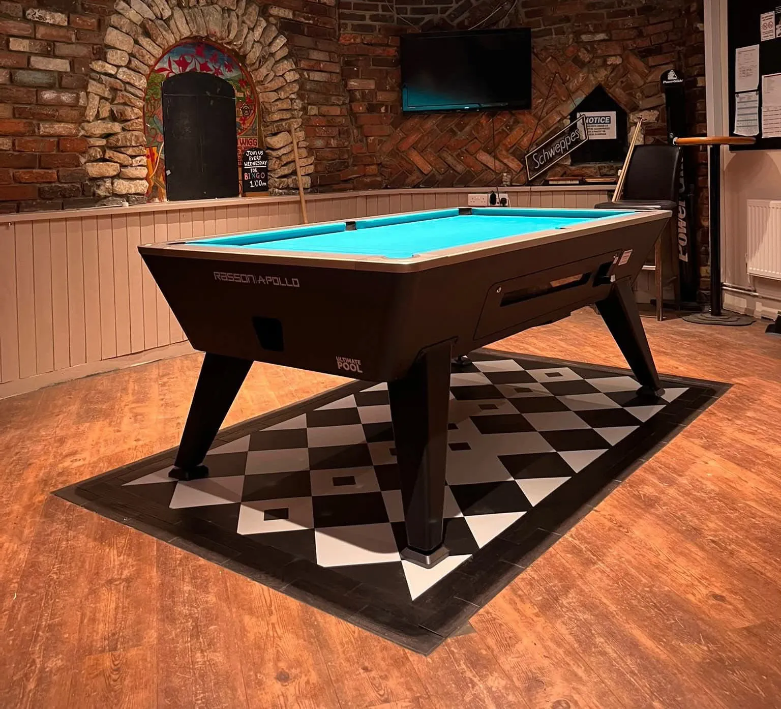 A pool table in a room with a brick wall.