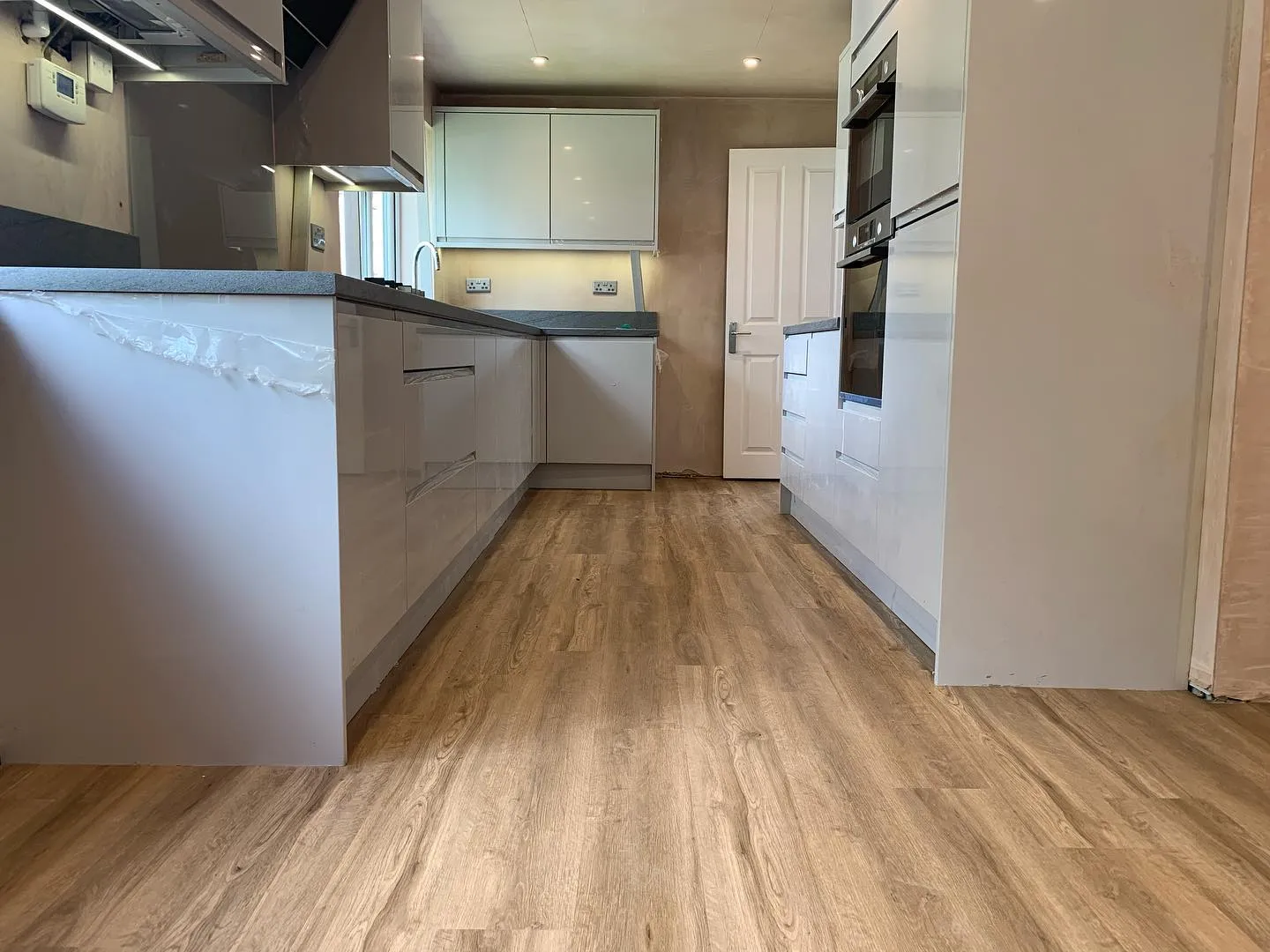 A kitchen with a wooden floor and white cabinets.