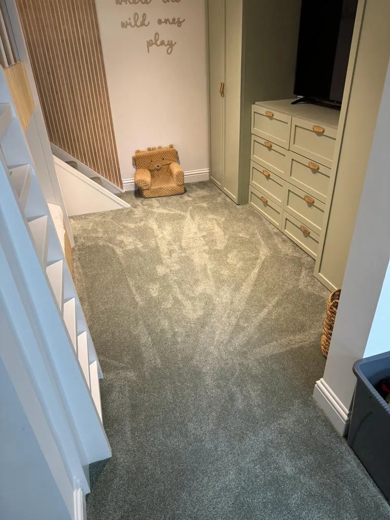 A room with a carpeted floor and a tv.